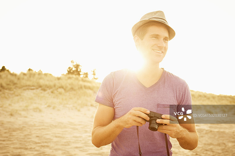 白人男子在海滩上拿着相机图片素材