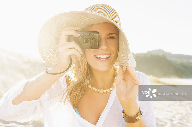 在海滩上使用数码相机的白人女性图片素材