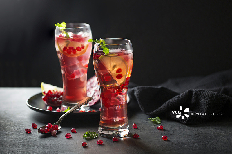 深色背景下的两杯冰镇石榴汁和柠檬片图片素材