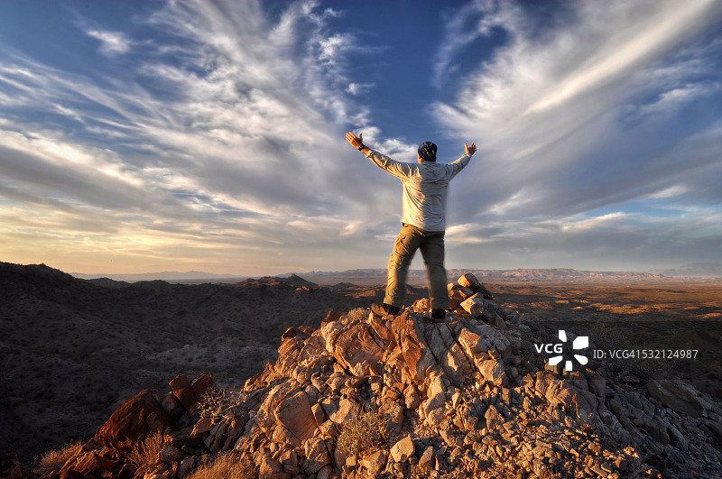 美国亚利桑那州，风山，男子在山顶上举起双臂图片素材