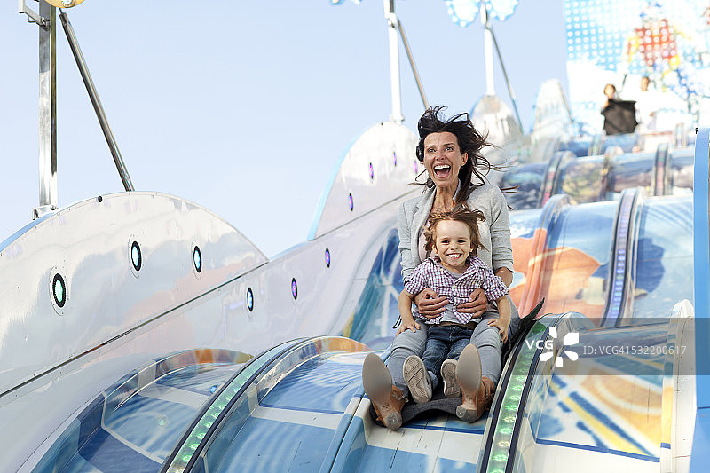 母亲和她的儿子在嘉年华的滑梯上图片素材