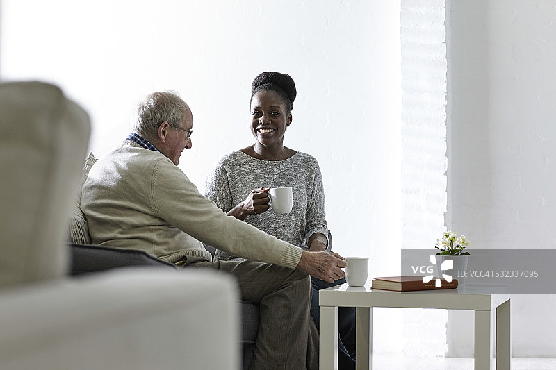 快乐的非洲裔女子和老年男子在家喝咖啡图片素材
