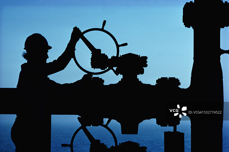 正在调节管道阀门的石油工人图片素材