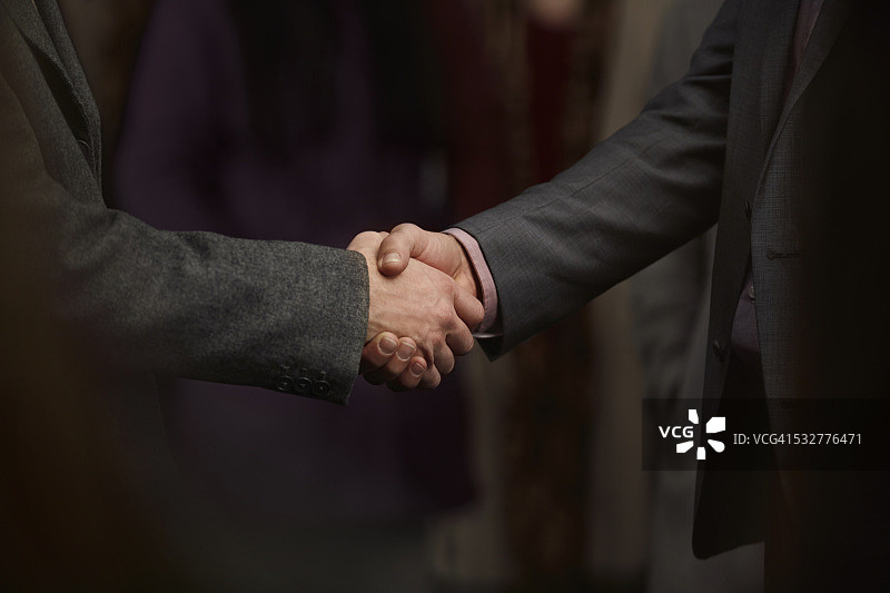 人群中两个男人握手的特写图片素材