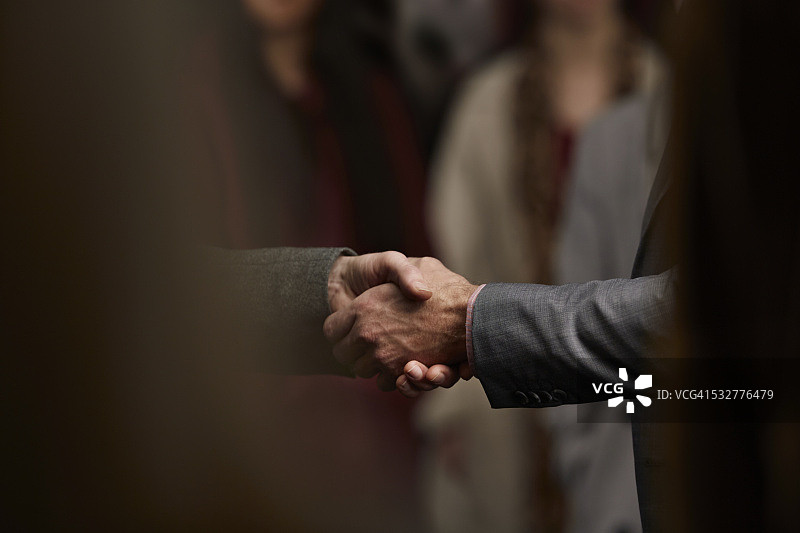 人群中两个男人握手的特写图片素材
