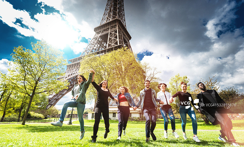 一群人在埃菲尔铁塔下的公园里跳跃图片素材
