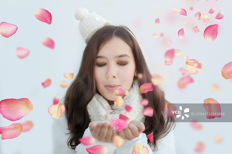 被粉红色玫瑰花瓣环绕的年轻漂亮的微笑少女图片素材