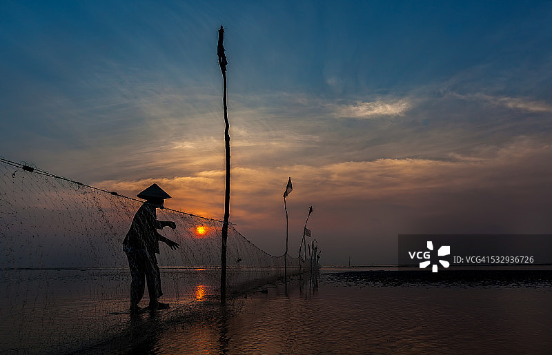 日出海滩上的渔网和女人剪影图片素材