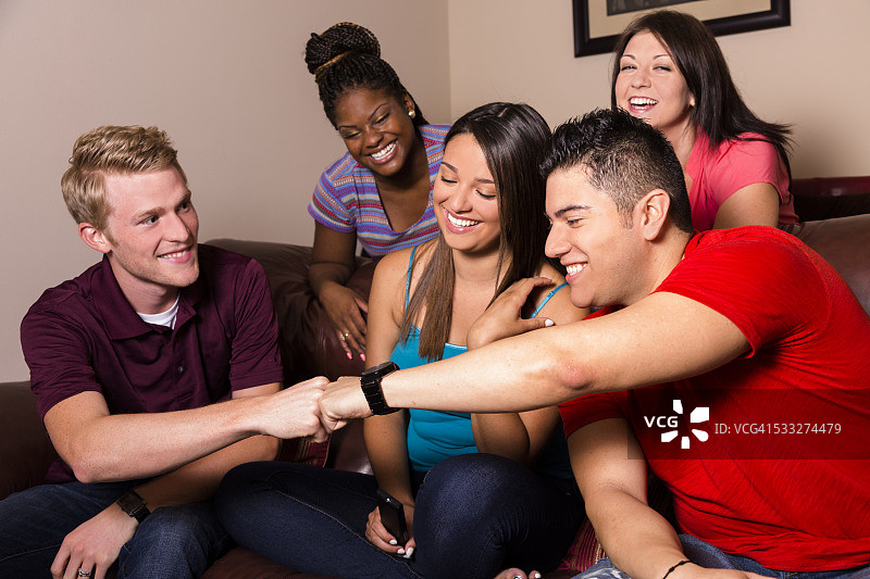 人际关系：20多岁的多民族朋友一起聚会看电视图片素材