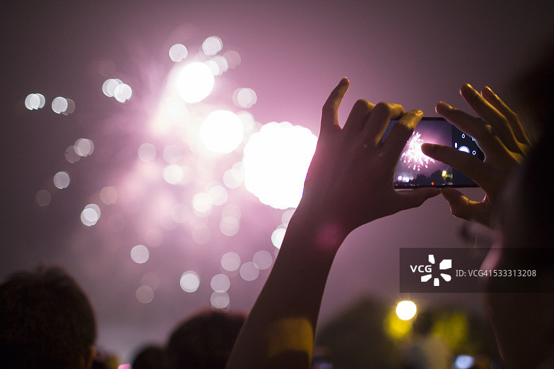 男人用新智能手机拍摄烟花图片素材