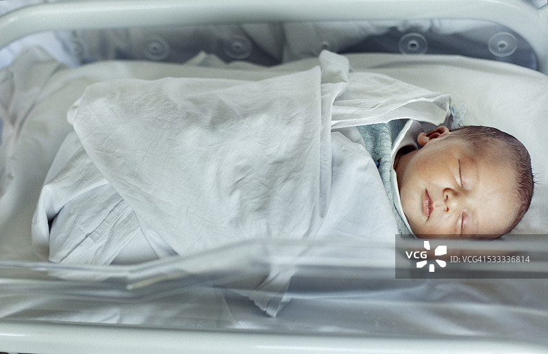 在医院婴儿床里睡着的新生男婴图片素材
