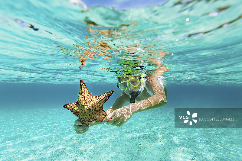 戴着呼吸管和面罩，拿着海星的女人图片素材