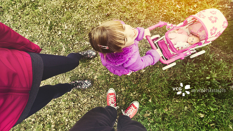 在公园里逗父母开心的小女孩图片素材