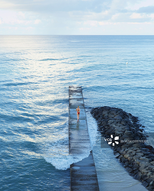 太平洋岛民妇女在海滩木码头上跑步的高角度景观图片素材
