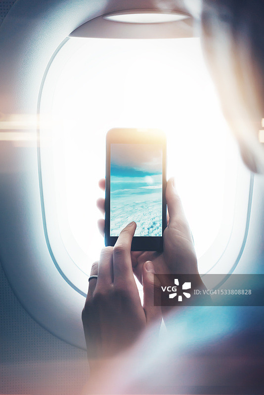 女性手持智能手机透过舷窗拍照特写图片素材