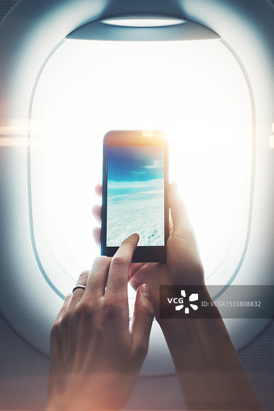 女性手持智能手机透过舷窗拍照特写图片素材