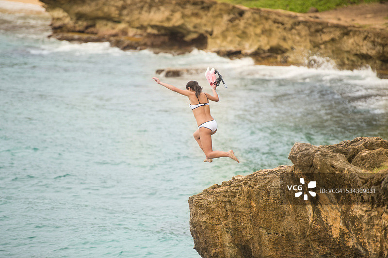 在夏威夷跳下悬崖，携带浮潜装备的迷人女性图片素材