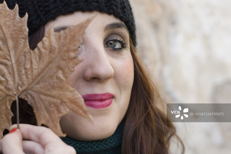 年轻女孩用叶子遮住眼睛图片素材