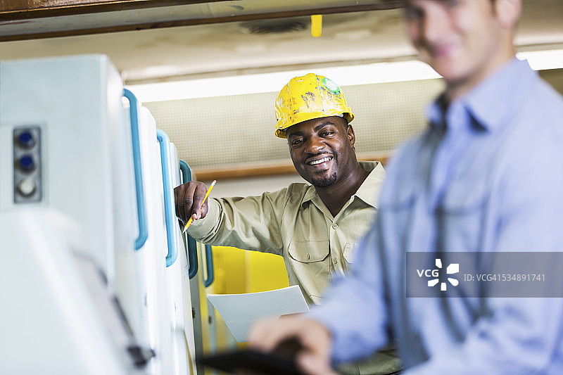 工人在制造工厂的机器旁工作图片素材