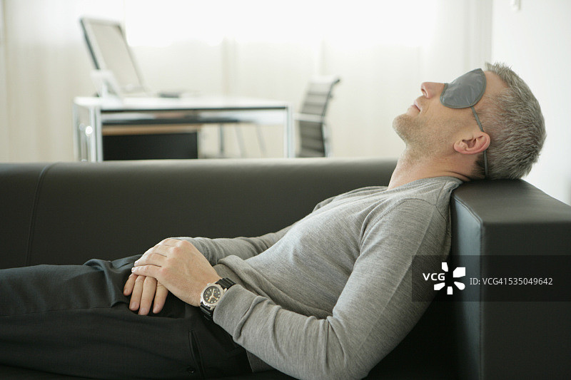 戴口罩的男人在沙发上睡觉图片素材