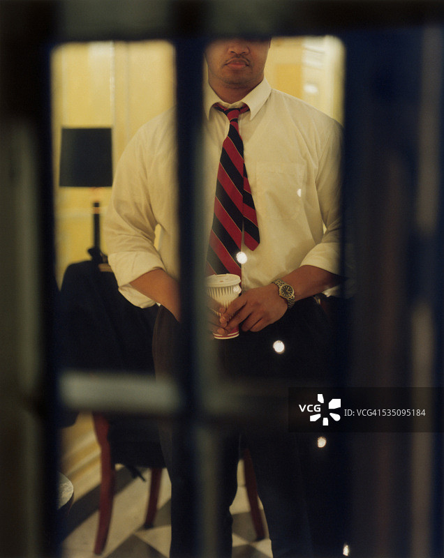 男子在玻璃门后手持咖啡图片素材
