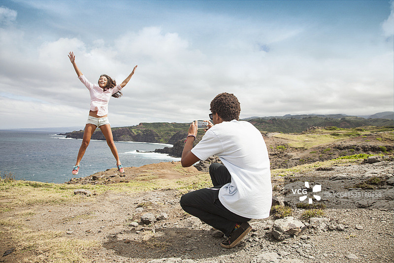 年轻男子拍摄跳跃的年轻女子图片素材