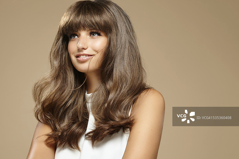 留着棕色波浪长发的年轻女子工作室肖像照图片素材