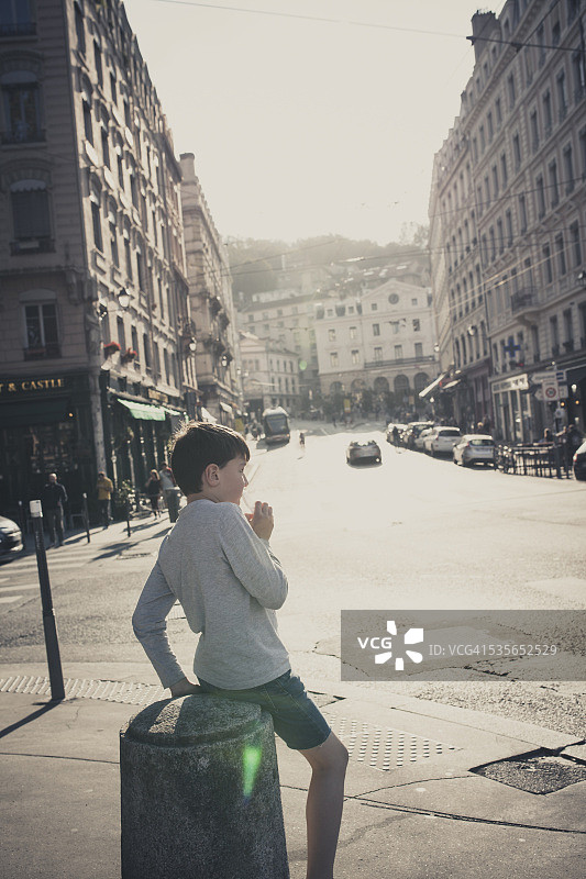 法国罗纳省里昂历史名镇中心坐在系缆柱上的男孩图片素材