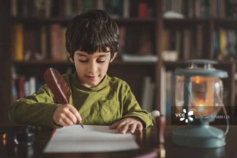 男孩用羽毛笔写信图片素材