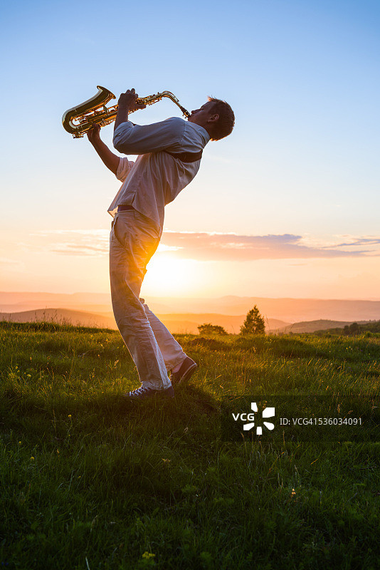 年轻男子在日落时于户外演奏萨克斯图片素材