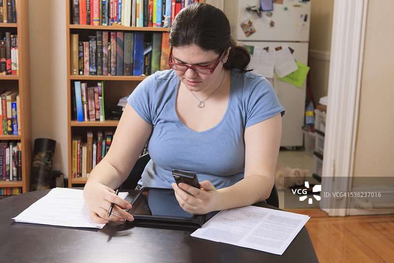 在家用智能手机和平板电脑工作的阿斯伯格综合征女人图片素材