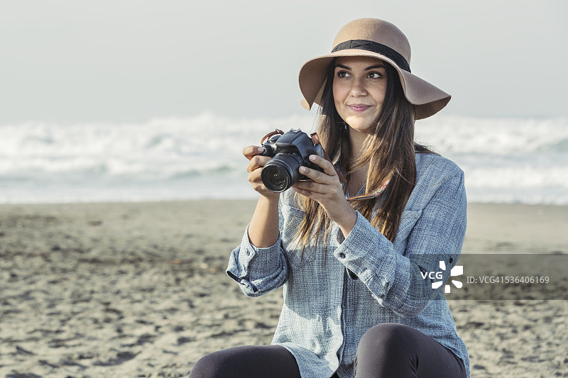 在海滩上拍照的年轻有魅力的拉丁裔男人图片素材
