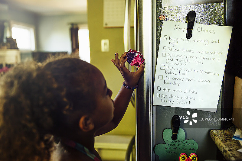 女孩看着冰箱上的家务清单图片素材