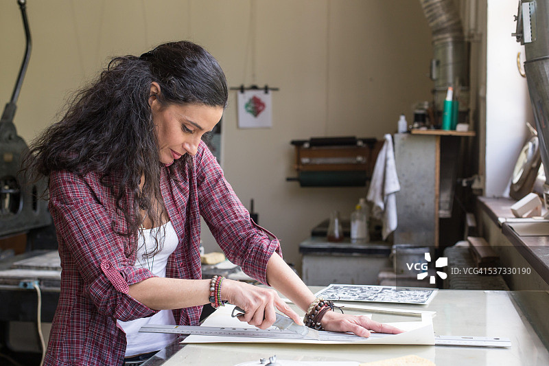 在工作室使用裁纸刀的女石印工人图片素材