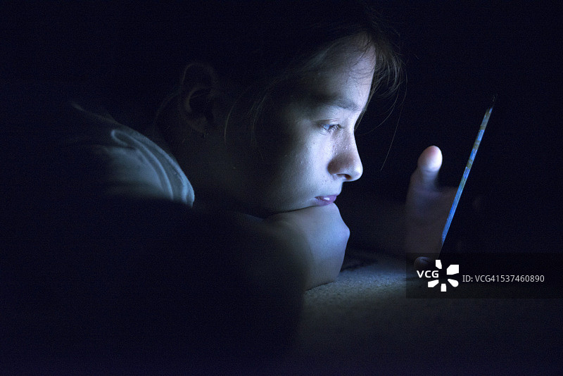 少女在床上用智能手机发送电子邮件图片素材