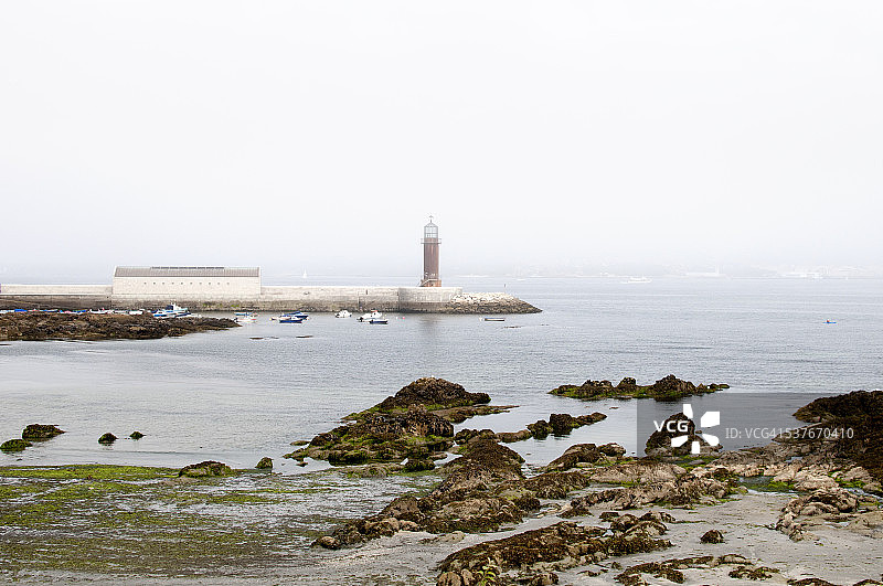 海边海岸线上的红色灯塔，雾天图片素材