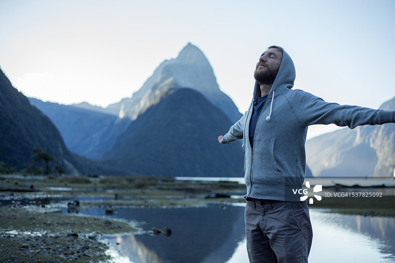米尔福德峡湾：伸出双臂的年轻男子图片素材
