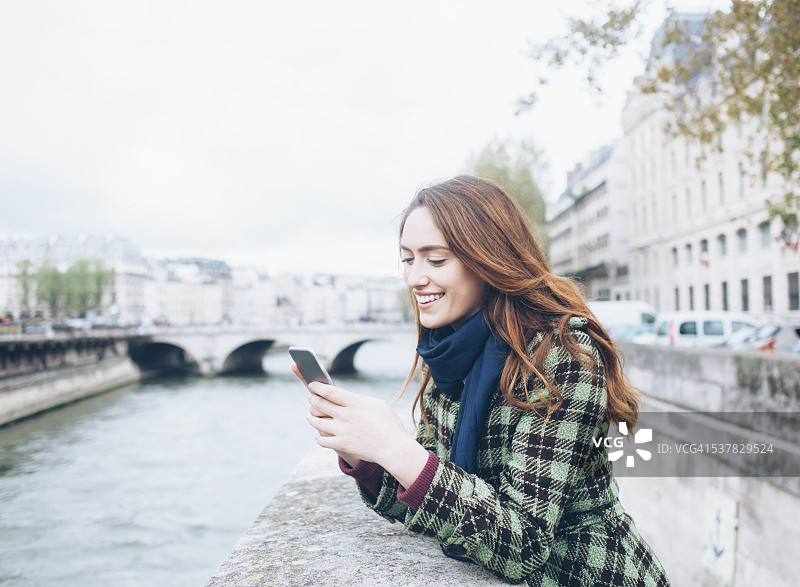 年轻女子在桥上使用智能手机图片素材