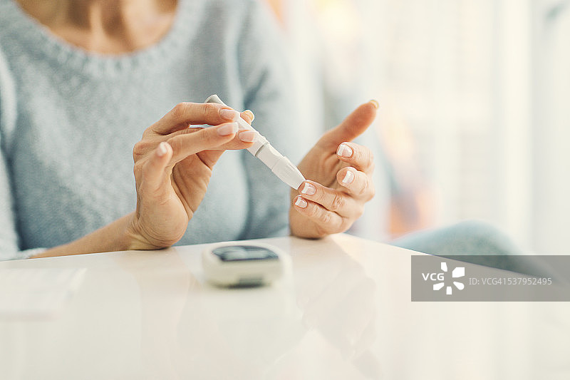 中年妇女在家进行血糖测试图片素材