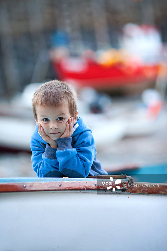 傍晚时分在船上看着镜头的男孩图片素材