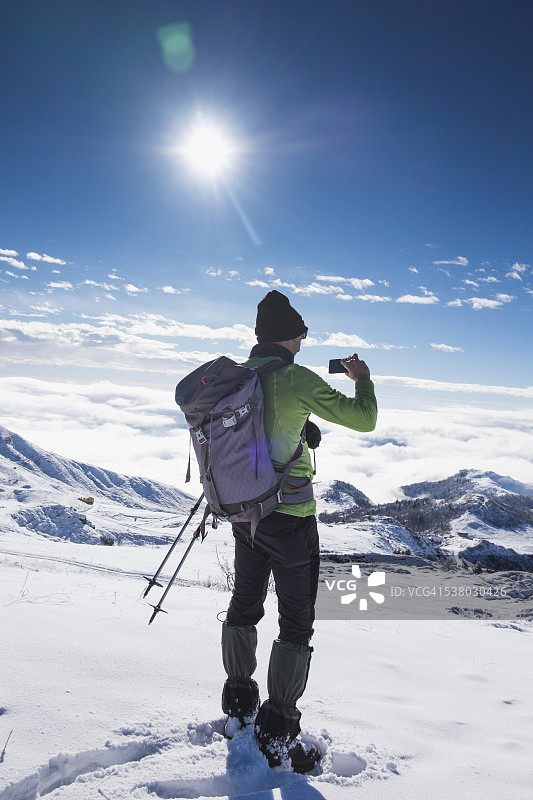 登山者在山顶上使用智能手机图片素材