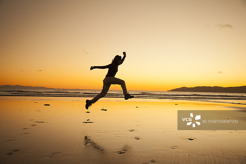 中国新西兰海滩上跳跃的女人剪影图片素材