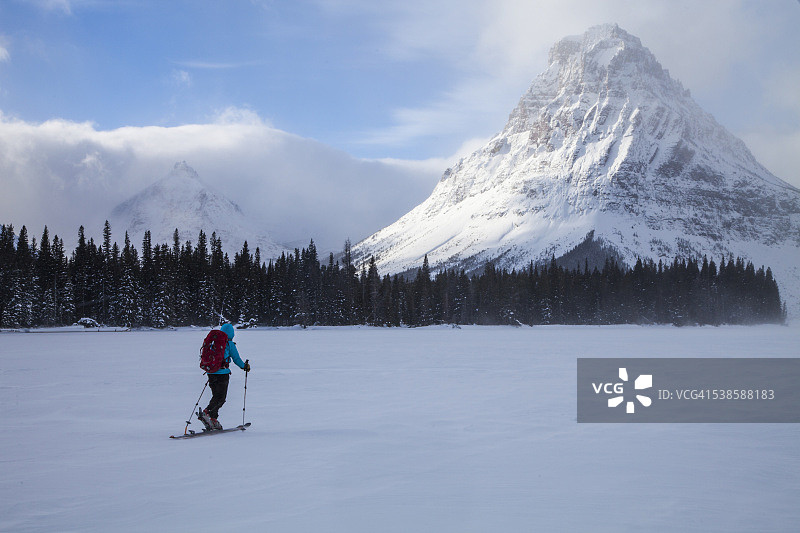 在冰川国家公园的两药湖上滑雪的女人，背景是锡诺帕山和彩绘蒂皮峰图片素材