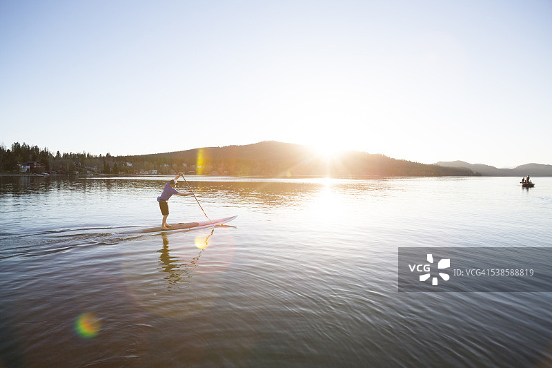 一位健壮的男人在蒙大拿州白鱼湖日落时分玩桨板运动图片素材