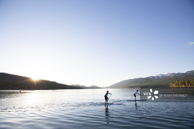 蒙大拿白鱼湖：健美男女日落时分玩立式桨板图片素材