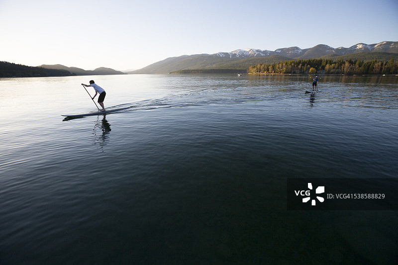 蒙大拿白鱼湖：健美男女日落时分玩立式桨板图片素材