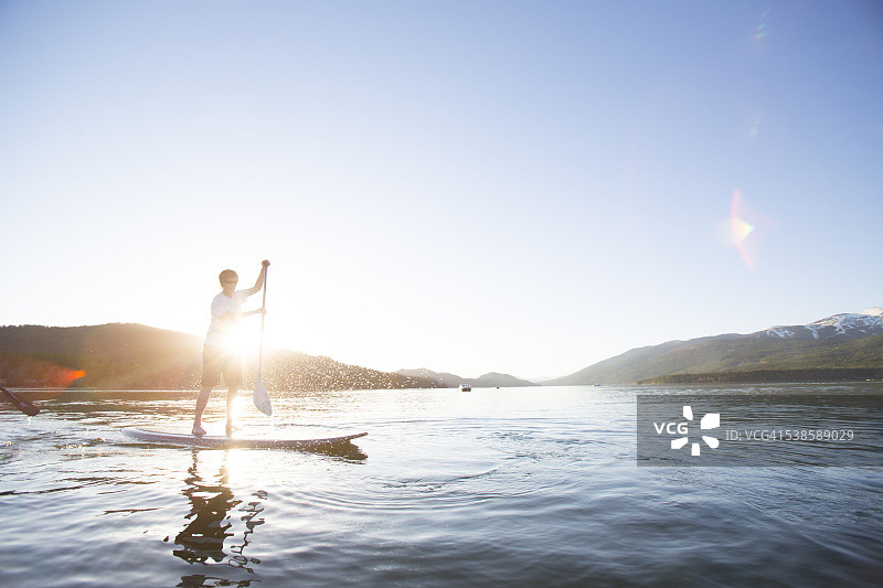 在蒙大拿州白鱼湖日落时分玩桨板的健美女性图片素材