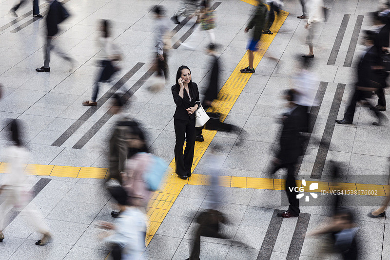 日本女人在通勤人群中打电话图片素材