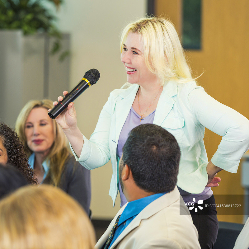 对着麦克风讲话的金发女子图片素材