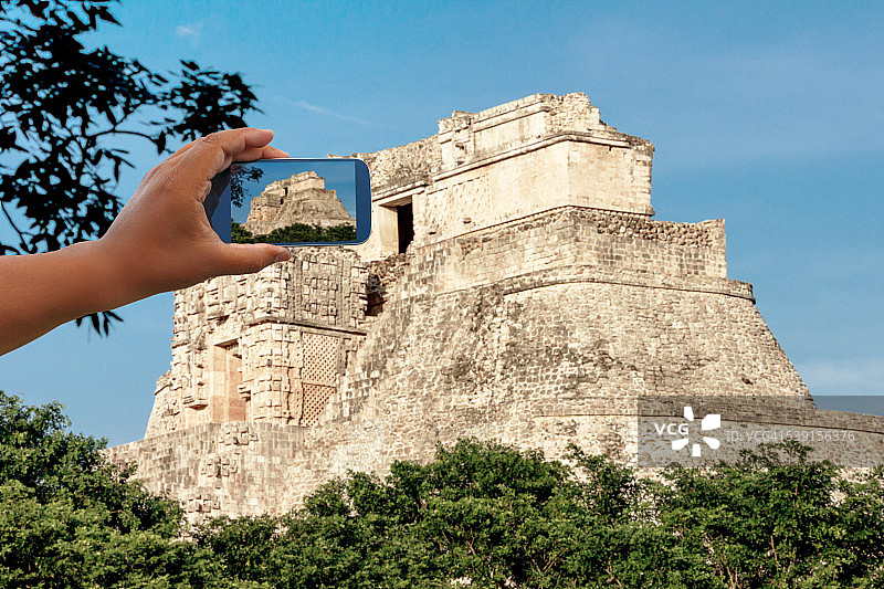 人手持手机拍摄墨西哥乌斯马尔的魔法师金字塔图片素材
